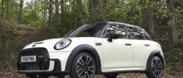 Bijeli Mini Cooper parkiran na cesti